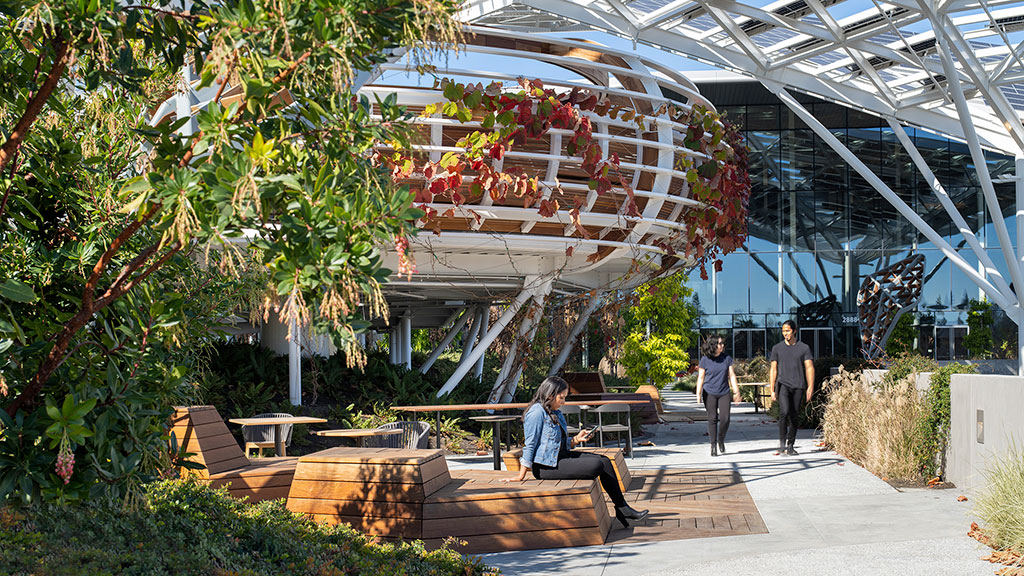 A group of people walking around a building with glass walls.